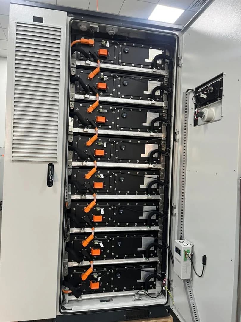 Battery rack with high-voltage connectors inside an energy storage cabinet.